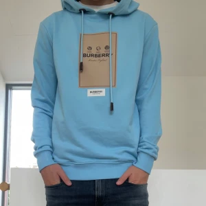 Ljusblå burberry Hoodie - Säljer en sjukt fet burberry hoodie i strl M. Hoodien har alla lappar på kvar även med taggs kvar från butiken med prislapp. Hör gärna av er vid frågor eller funderingar!! den är INTE ÄKTA!!