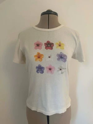 Söt somrig T-shirt topp med tryck av blommor y2k vintage stol pastell sommar  - Fin somrig T-shirt med tryck av blommor. Ribbad i 100% bomull. Något använd, i mycket bra skick. 