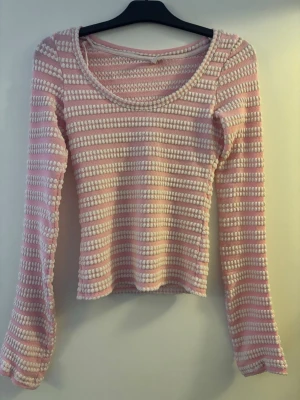 Rosa och vit randig långärmad topp - Supersöt långärmad topp med rosa och vita ränder. Toppen har en rundad ringning och är gjord i ett mjukt, stretchigt material med struktur. Perfekt för dig som gillar en feminin och trendig stil.