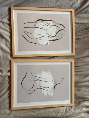 Två abstrakta tavlor med träram - Säljer två stilrena abstrakta tavlor med ljusa träramar. Motiven består av svarta linjer och vita färgfält på beige bakgrund, vilket ger en modern och minimalistisk känsla. Perfekta som väggdekoration i hemmet. 25*35
