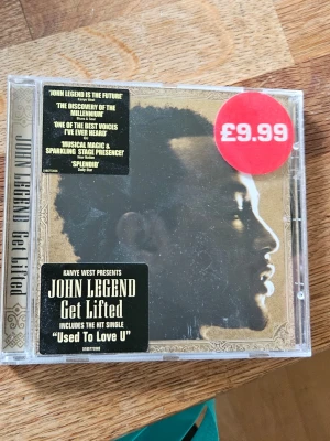John Legend Get Lifted CD-album - Säljer CD-albumet 'Get Lifted' av John Legend, presenterat av Kanye West. Albumet har en plastfodral med guldfärgad ram och svart etikett. Innehåller hitlåten 'Used To Love U'. Perfekt för dig som gillar soul och R&B.