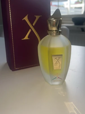 Xerjoff Naxos parfym 100ml - Lyxig parfym från Xerjoff, modellen Naxos. Flaskan är frostad vit med guldfärgad metallkork och detaljer. Innehållet är gult och flaskan har en elegant, kantig form med exklusiv känsla. Kommer med originalförpackning i vinröd och guld. Har andvänds lite