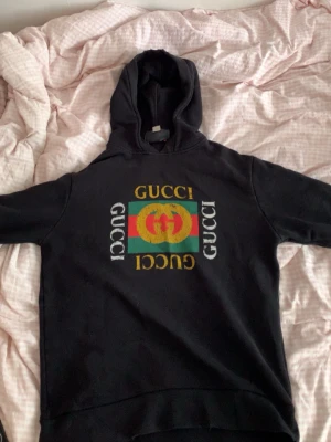 Svart hoodie från Gucci  - Cool svart hoodie från Gucci, Klassisk huva och ribbade muddar. Materialet är mjukt och bekvämt, perfekt för att sticka ut i mängden. Tillverkad i Italien.