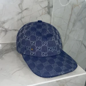 Blå mönstrad keps 🧢  - Säljer en snygg blå keps med det klassiska mönstret över hela kepsen. Kepsen har böjd skärm och är tillverkad i ett denimliknande material. Perfekt för dig som vill ha en trendig och exklusiv accessoar.