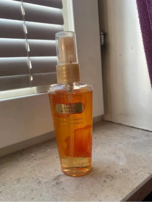 Amber Romance mist från Victoria's Secret - Amber Romance Fragrance Mist från Victoria's Secret i en genomskinlig plastflaska med guldigt spraylock. Doften har varma, bärnstensfärgade toner och flaskan har en snygg orange nyans. Perfekt för dig som gillar söta och sensuella dofter.