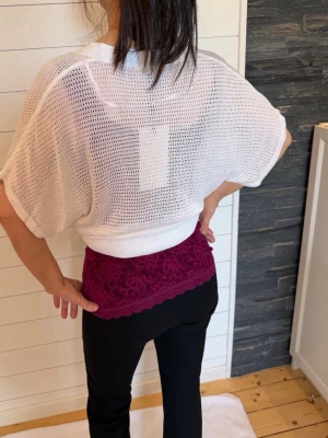 Vit kortärmad kofta med knappar - Ny oanvänd: Snygg vit kofta i meshstickat material med korta, vida ärmar och tre dekorativa knappar framtill. Koftan har en djup V-ringning och avslappnad passform, perfekt att slänga över ett linne eller topp för en trendig lager-på-lager-look.