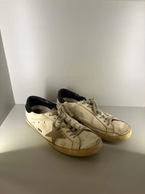 Vita Golden Goose sneakers med stjärna - Snygga vita sneakers från Golden Goose. Tillverkade i läder med slitna detaljer för en cool, avslappnad look. Men skorna har en del defekter som du kan se på bilderna. 