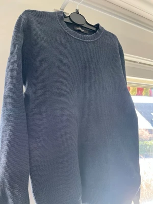 Mörkblå stickad tröja Dressmann - Mörkblå stickad tröja från Dressmann med rund hals och diskret strukturmönster.