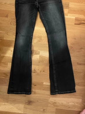 Svarta bootcut jeans från Gina Tricot - Bootcut jeans i mörkgrå färg med ljusningar på låren från Gina Tricot. Fick dessa i födelsedagspresent men gillade inte dom super mycket så de blev att de inte kom till användning. Endast använt 1 gång. Inga slitningar och inte trasiga. De har knappar på bakfickorna och är i storlek 170.