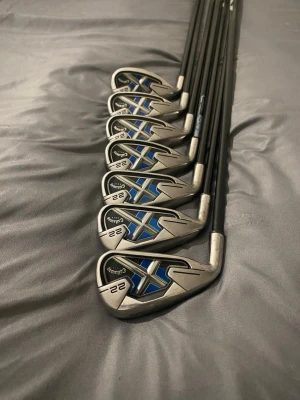 Callaway X-22 Irons 5-PW + SW//Vänster - Säljer ett Callaway X-22 Irons 5-PW + Sand Wedge ett riktigt populärt och förlåtande järnset, som fortfarande håller hög klass i 2026. Med perimeter weighting, tunn face och bred sole får du hög bollhastighet och enkel launch även vid miss-hits. Setet glider smidigt genom gräset från fairway och rough, och den ger bra självförtroende vid address. Så du får något förlitande du kan spela för väldigt länge och värd varje peng.   Skaft flex är regular  VÄNSTERHÄNT Teknik: Perimeter weighting för hög