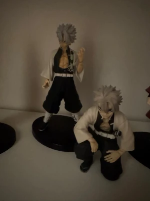 Sanemi anime figure Demon slayer kny - Två detaljerade sanemi figurer med vitt spretigt hår, svarta byxor och vita kimonoliknande jackor. Båda har svarta bälten och accessoarer, en står och en sitter på huk. Perfekt för samling. 💞Har tyvärr inte lådan 