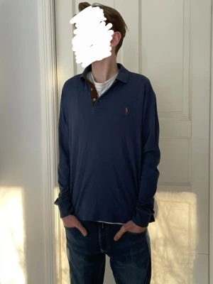 Polo Ralph Lauren tröja - Säljer denna långärmade slimfit pikén från Polo ralph lauren. Tröjan är blå/mörkblå (mer lik färgen i de sista bilderna än första) och har polo märket på vänstra bröstet samt en button up krage vid halsen. Tröjan har inga defekter och är i storlek M men passar bäst åt S, modellen är 173 cm lång. Hör gärna av er vid frågor😁 Pris kan diskuteras vid snabb affär👍
