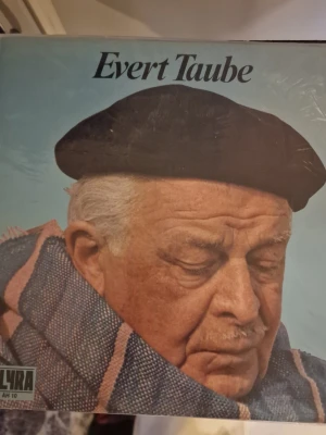 Evert Taube vinylskiva LP - Evert Taube vinylskiva LP. Skivan är utgiven på skivbolaget Lyra. Omslaget visar Evert Taube på framsidan och baksidan listar låttitlar samt mindre bilder. Passar för uppspelning på skivspelare som klarar LP-format.