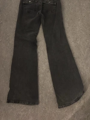 Mörkgråa bootcut jeans med rå kant  - Säljer ett par mörkgråa bootcut jeans med råa kanter nertill och snygga bakfickor. Pågrund av att dom har blivit för småa för mig passformen är utsvängd från knät och ner