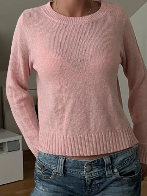 Ljusrosa stickad tröja från H&M - Mysig ljusrosa stickad tröja från H&M med rund halsringning och långa ärmar. Tröjan har ribbade muddar vid ärmslut och nederkant. Perfekt för lager på lager och enkel att matcha med jeans eller kjol.