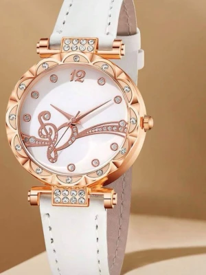 Två glittriga klockor i roséguld - Säljer två snygga klockor i roséguld med glittriga detaljer. Den ena har vitt läderband och musiknot-design på urtavlan, den andra har metallarmband och romerska siffror. Båda har stenar runt urtavlan och elegant look. Perfekt accessoar för att lyfta din outfit.