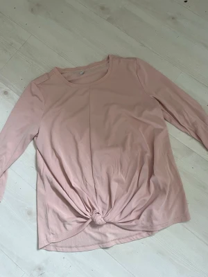 Ljusrosa långärmad topp från ONLY - Supersöt ljusrosa långärmad topp från ONLY med rund halsringning och knutdetalj framtill. Tillverkad i mjukt material som känns skönt mot huden. Perfekt att styla med jeans eller kjol för en chill look.