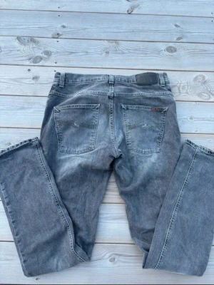 Grim Tim Nudie Jeans  - Säljer dessa grå jeans från Nudie i modellen Grim Tim med klassisk femficksdesign och raka ben. Mycket bra skick