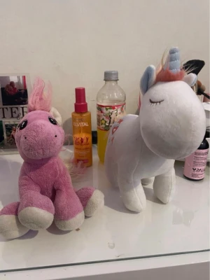 Två mjukisdjur enhörningar - Säljer två gulliga mjukisdjur i form av enhörningar. En är rosa med vit man och svans, stora broderade ögon och mjuka ben. Den andra är vit med blå horn, rosa man och svans samt broderade stjärnor och hjärta på sidan. Perfekta som dekoration eller gosedjur.