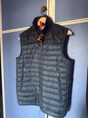 Parajumper daytripper väst Strl. S - Snygg mörkblå dunväst med ståkrage och två dragkedjeförsedda fickor framtill. Västen har quiltad design och stängs med dragkedja. Perfekt för lager-på-lager och ger en sportig look. Materialet är lätt och isolerande.