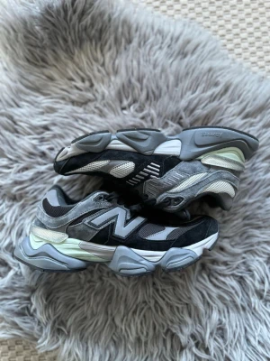 New Balance grå och svarta sneakers - Chunky sneakers från New Balance i olika nyanser av grått och svart med mesh- och mockadetaljer. Snygg design med stora N-loggan på sidan och robust sula för extra komfort. Perfekta för dig som gillar streetwear och sportig stil. Aldrig använda!