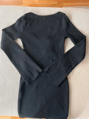 Svart ribbad långärmad klänning - Säljer en svart ribbad klänning med lång ärm och rundad urringning. Klänningen är figurnära och har en enkel, stilren design som passar perfekt till olika tillfällen. Materialet är stretchigt och bekvämt.
