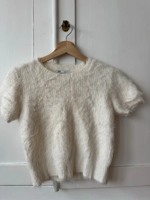 Vit fluffig stickad tröja från Zara - Supermjuk och fluffig kortärmad stickad tröja från Zara i en krämvit färg. Storlek L ( mycket liten i storlek, snarare en XS ) . Fint skick!