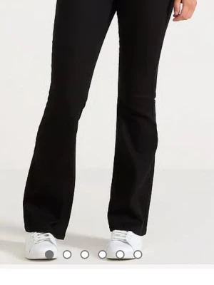 Svarta bootcut jeans - Snygga svarta bootcut jeans med utsvängda ben och klassisk femficksdesign. Jeansen har en hög midja och är tillverkade i ett stretchigt material som ger en bekväm passform. Perfekta för dig som gillar en tidlös och trendig look. Storkek 170