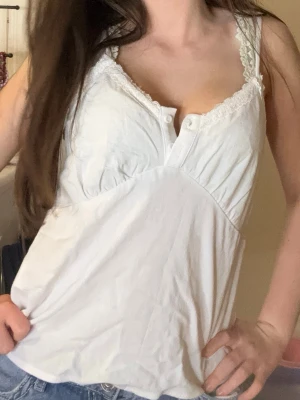 Vit spetsdetaljerad linnetopp - Söt vit linnetopp med spetsdetaljer längs urringningen och knappar framtill ❤️helt ny aldrig använd har prislapp på! 