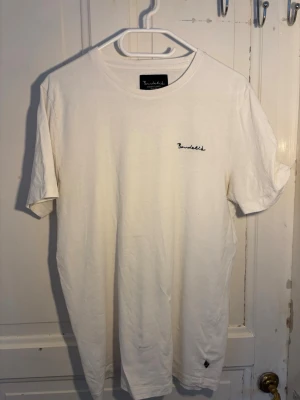 Vit t-shirt från Bondelid - Obs säljes snabbt, är öppen för seriösa bud Klassisk vit t-shirt från Bondelid med svart broderad logga på bröstet. T-shirten har rund halsringning och korta ärmar. Tillverkad i mjuk bomull för en skön känsla och enkel stil. (Passar även Strlk S)