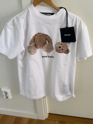 Vit Palm Angels t-shirt med nalletryck - Säljer en vit t-shirt från palm angels. Varan är äkta och den är ALDRIG använd. Tags o allt kvar. Säljer pågrund av överflöd.