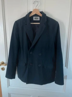 Jacka / kavaj Weekday - Jacka i kavaj-stil i en mörkblå, nästan svart färg. Från Weekday i storlek M. Innehåller ull som värmer och har även en innerficka.  