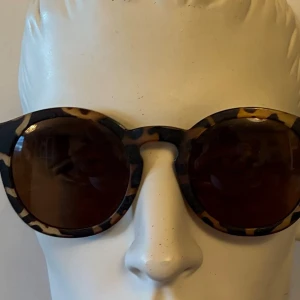 Dansk design Polaroid Bruna solglasögon med sköldpaddsmönster  - Snygga solglasögon med rundade bågar i klassiskt sköldpaddsmönster. Glasen är mörkbruna och bågarna har en trendig retrostil. Perfekta för att lyfta din look med en cool vintagekänsla.