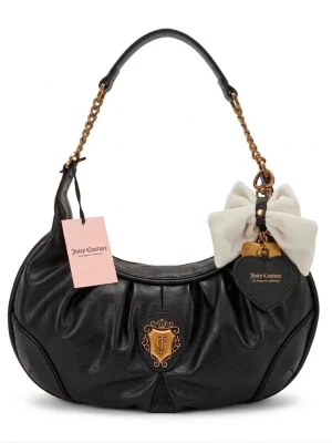 Juicy Couture svart axelväska med rosett - Juicy Couture handväska i svart skinnimitation med guldfärgade detaljer och kedja. Väskan har en stor vit rosett och ett hjärtformat hänge. Klassisk Juicy Couture-logga framtill och snygg bågformad design.