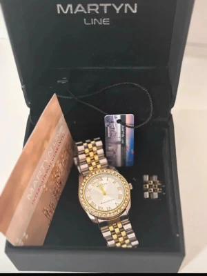 Martyn Line klocka i guld och silver - Stilren klocka från Martyn Line med tvåfärgad länk i guld och silver.               ☑️Stilren och lyxig look   ✔ Kommer med box   ✔ Perfekt till vardag eller fest.  📌 Skick: Bra, behöver nytt batteri