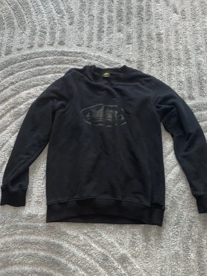 Svart sweatshirt med tryck - Svart sweatshirt från Gul med rund halsringning och ribbade muddar. På bröstet finns ett svart ton-i-ton tryck med ett ovalt motiv. Perfekt för en avslappnad och stilren look. Och den är äkta