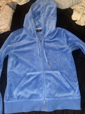 Blå velour hoodie från Juicy Couture - Säljer denna pågrund av att den inte används. Den har en fläck på luvan som troligen går att ta bort (ska försöka ta bort innan den skickas) den är använd men i väldigt bra skick fortfarande len och fin