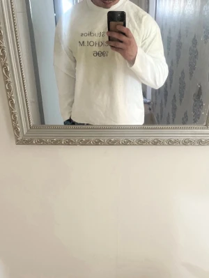 Vit långärmad Acne Studios t-shirt - Vit långärmad t-shirt från Acne Studios med tryck 'Acne Studios STOCKHOLM 1996' på bröstet. Klassisk rund hals och relaxed fit. Perfekt för dig som gillar minimalistisk och stilren design.