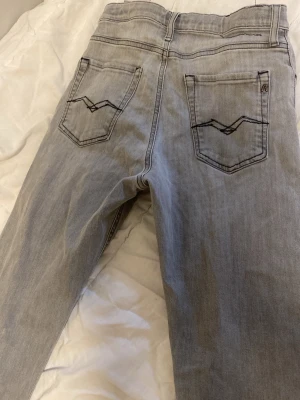 Ljusgrå jeans från Replay - Pasar 11-13 åringar.Snygga ljusgrå jeans från Replay med klassisk femficksdesign och coola detaljer på bakfickorna. Jeansen har en rak passform och är tillverkade i mjukt denimtyg som känns bekvämt hela dagen.