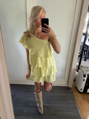 Zara Gul one shoulder volangklänning - Snygg gul kortklänning med volanger och one shoulder-design. Klänningen har flera lager volanger och en asymmetrisk axel, vilket ger en trendig och lekfull look. Perfekt för sommarens alla tillfällen.