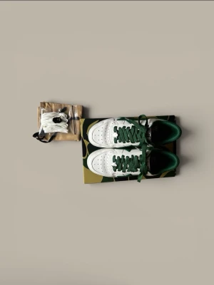 BAPE STA vita och gröna sneakers  - Säljer ett par äkta BAPE STA sneakers i vitt och grönt skinn med ikonisk stjärndesign på sidorna. Skorna har gröna snören, grönt innerfoder. Kommer med originalkartong och dustbag med BAPE-logga och ett par vita skosnören. Perfekta för dig som gillar streetwear. Storlek 43/44