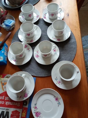 Kaffeservis med blommönster, 8 delar - Säljer en klassisk kaffeservis med åtta koppar och tillhörande fat i vitt porslin. Alla delar har ett fint rosa och lila blommönster och rund form. Perfekt för fika med vänner eller familj.samt tre extra små fat.