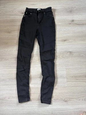 Svarta skinny jeans - Säljer ett par svarta skinny jeans med klassisk femficksdesign och smal passform. Jeansen har normal midja och dragkedja med knapp framtill. Perfekta för dig som gillar en stilren och enkel look.