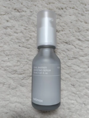 Celimax Dual Barrier Boosting Serum - Minimalistisk och stilren flaska med Celimax Dual Barrier Boosting Serum, 30 ml. Flaskan är frostad i grått med vitt tryck och har en praktisk pump. Perfekt för dig som vill stärka hudbarriären och ge huden extra fukt.