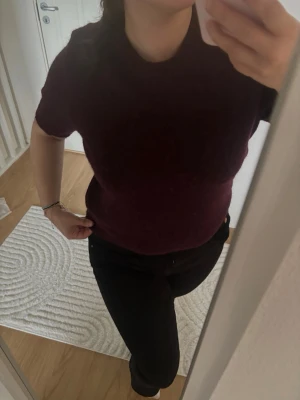Vinröd stickad kortärmad topp - Vinröd stickad topp med korta ärmar och rund halsringning. Enkel och stilren modell som passar perfekt till jeans eller kjol. Mjuk och bekväm, perfekt för dig som gillar en clean look. Från Gina trickot