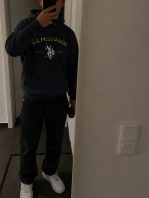 Marinblå hoodie från U.S. Polo Assn - Snygg marinblå hoodie från U.S. Polo Assn med gul och vit liga. Klassisk skön huva. Perfekt med de jeansen som ligger ute för en skön stil. Vid frågor är det bara att skriva:)