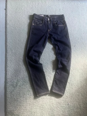Mörkblå jeans från Replay - Snygga mörkblå jeans från Replay med klassisk femficksdesign och kontrastsömmar. Jeansen har rak passform och är tillverkade i ett slitstarkt denimtyg. Perfekta för dig som gillar stilrena och tidlösa jeans.