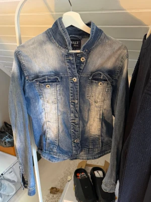 Blå jeansjacka från Salt - Snygg blå jeansjacka från Salt med klassisk tvättad look och raka linjer. Jackan har två bröstfickor med lock och knappar samt knäppning framtill. Perfekt för dig som gillar en tidlös och avslappnad stil.