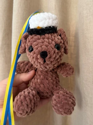 Studenthänge – Virkad hund med studentmössa - Virkad studentplushie med studentmössa och blågula band. Perfekt som studentpresent eller att hänga runt halsen på studenten 🤍Handgjord, därför kan små variationer förekomma.