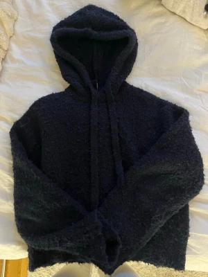Boucléstickad hoodie - Superfin stickad hoodie i marinblå från H&M! Designen ser lite nopprig ut från början (se bild 3) och kan även ha fått lite noppror under användning men ingenting som syns när man har på sig sen! 